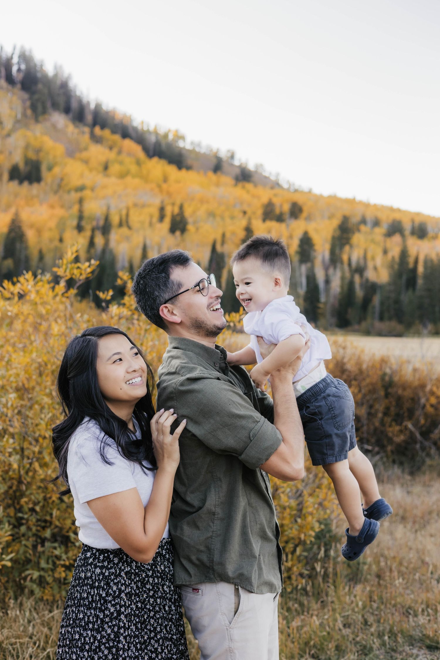 A family shares joyful moments together against a backdrop of autumn foliage in the mountains.