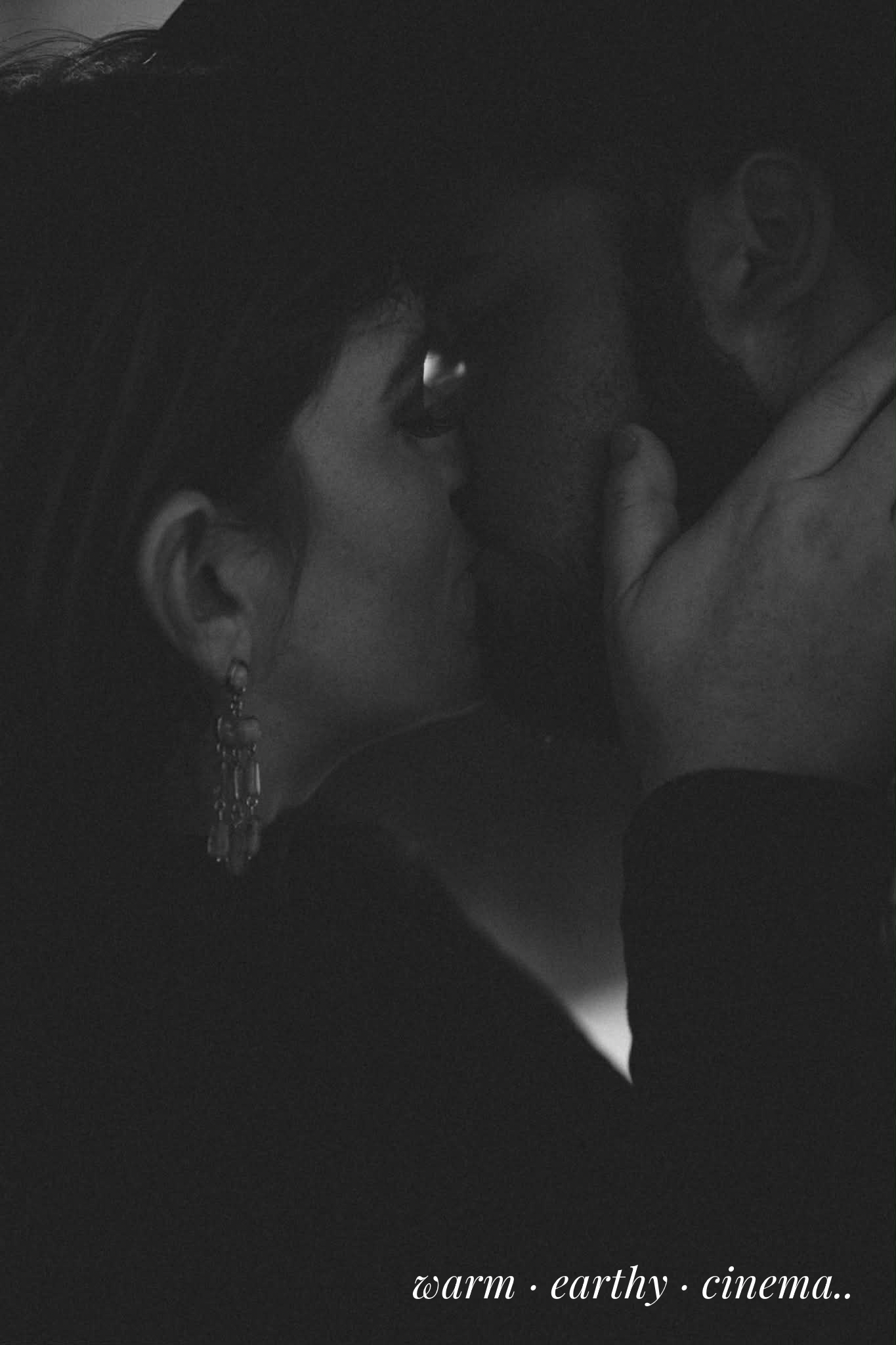 Close-up of couple kissing in low light with soft, cinematic tones