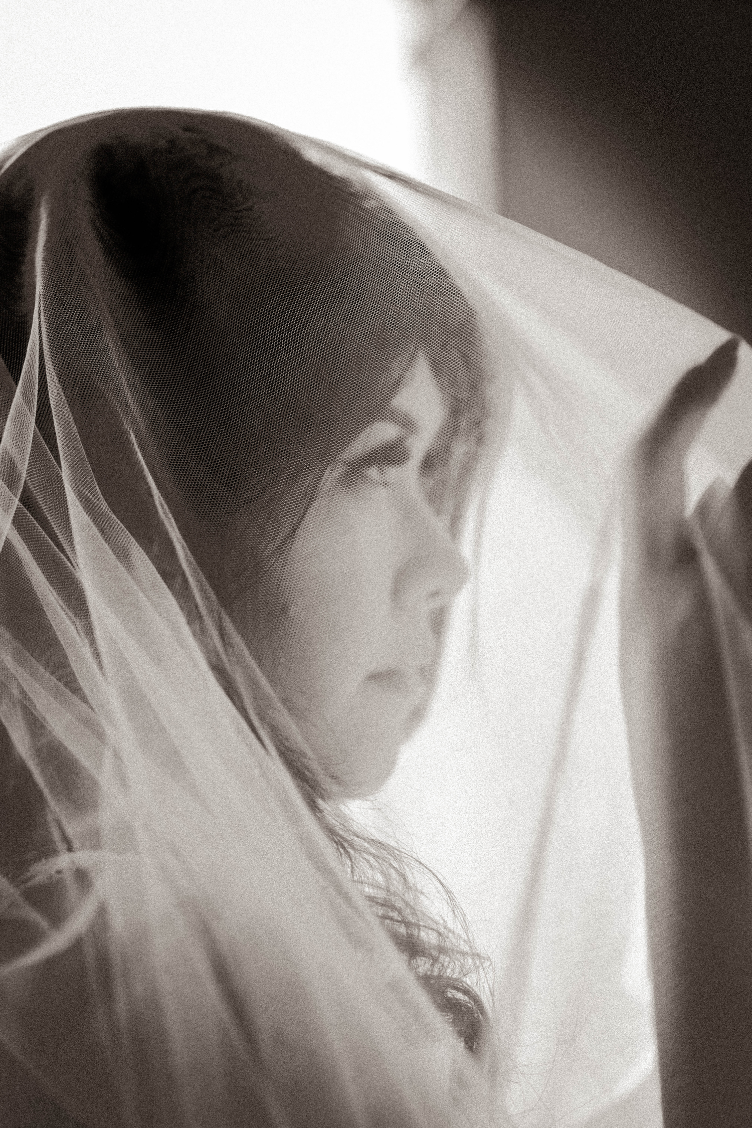 Dreamy black and white portrait of a bride gazing through a flowing wedding veil.