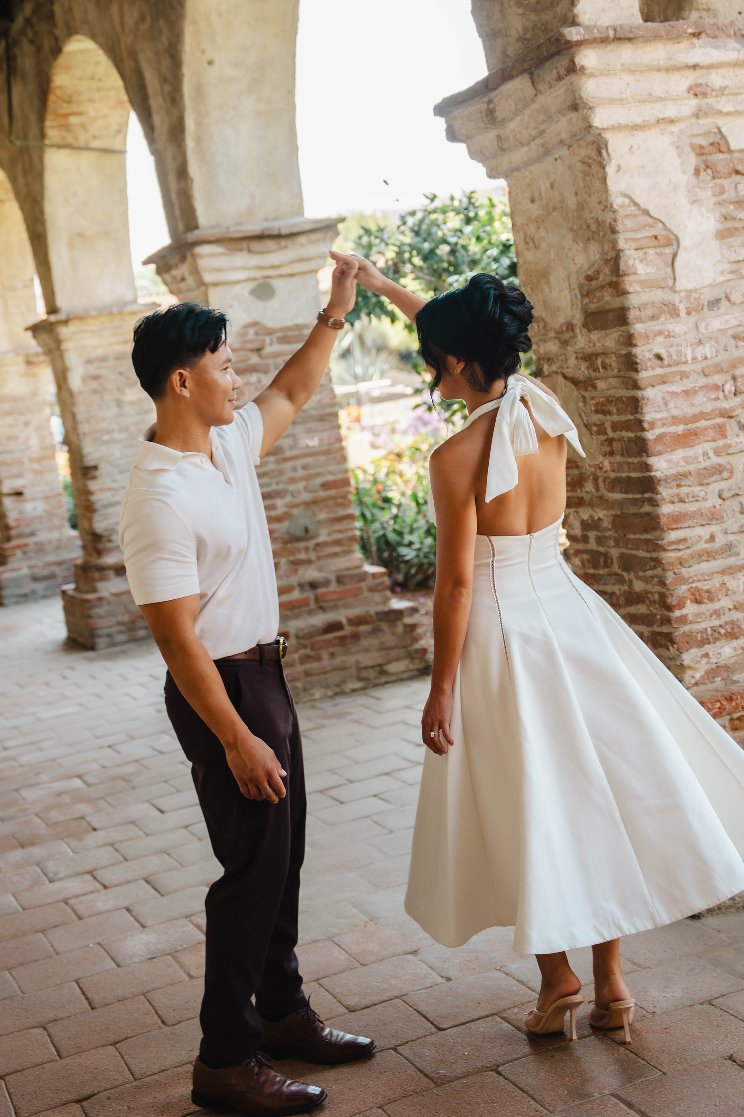 Couple dancing elegantly under brick arches at historic Mission San Juan Capistrano.