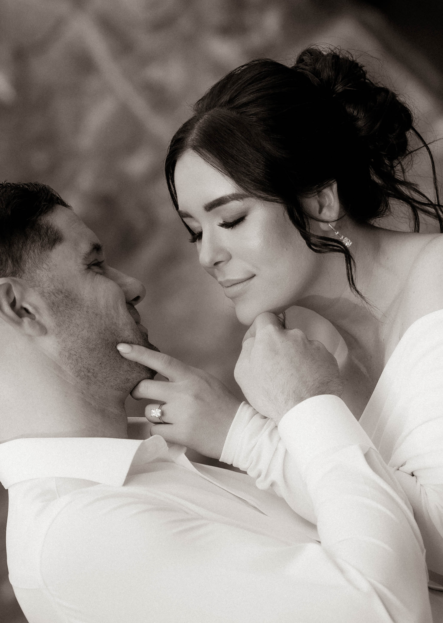 Intimate black and white close-up of bride and groom almost kissing, bride wearing diamond engagement ring.