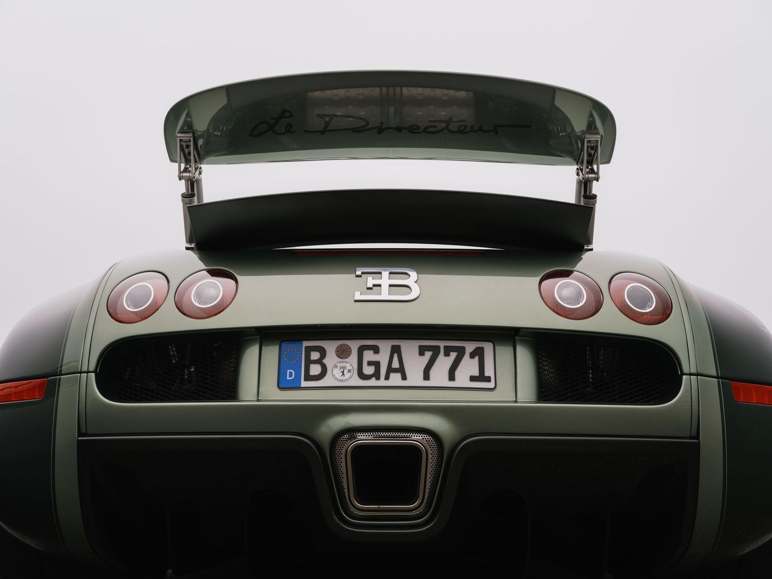 Rear view of a Bugatti Veyron supercar with raised spoiler, German license plate B GA 771, and quad taillights.