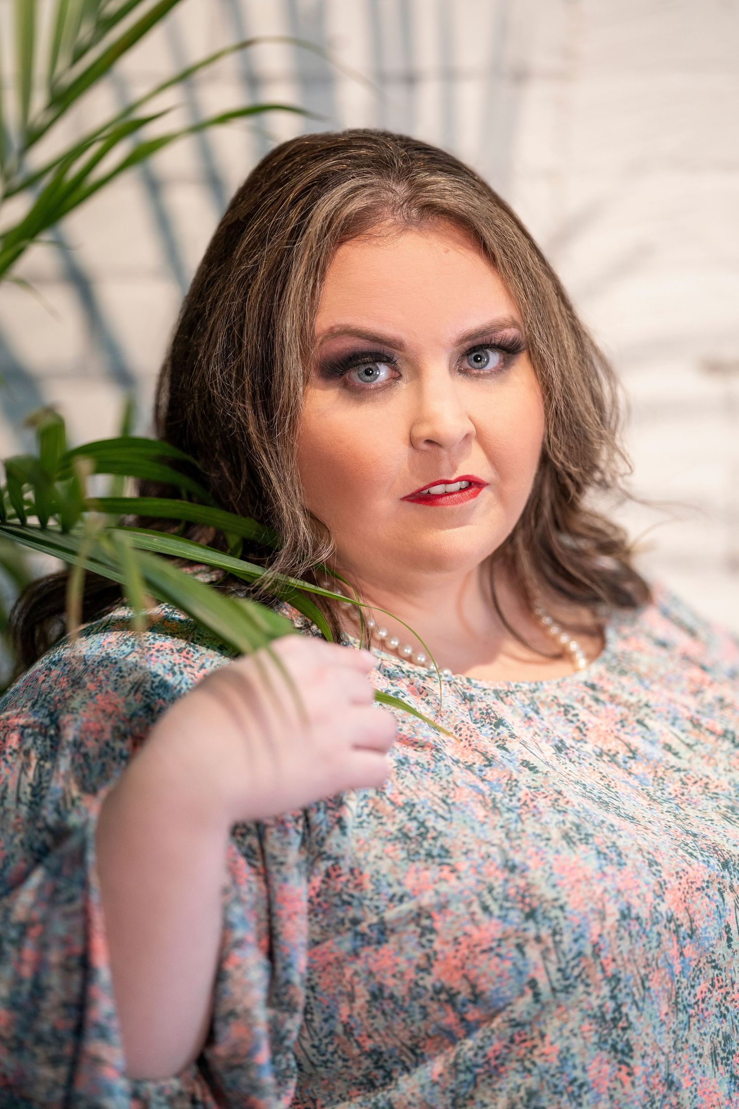 Close-up portrait shots showing floral dress and glamorous makeup in soft lighting.