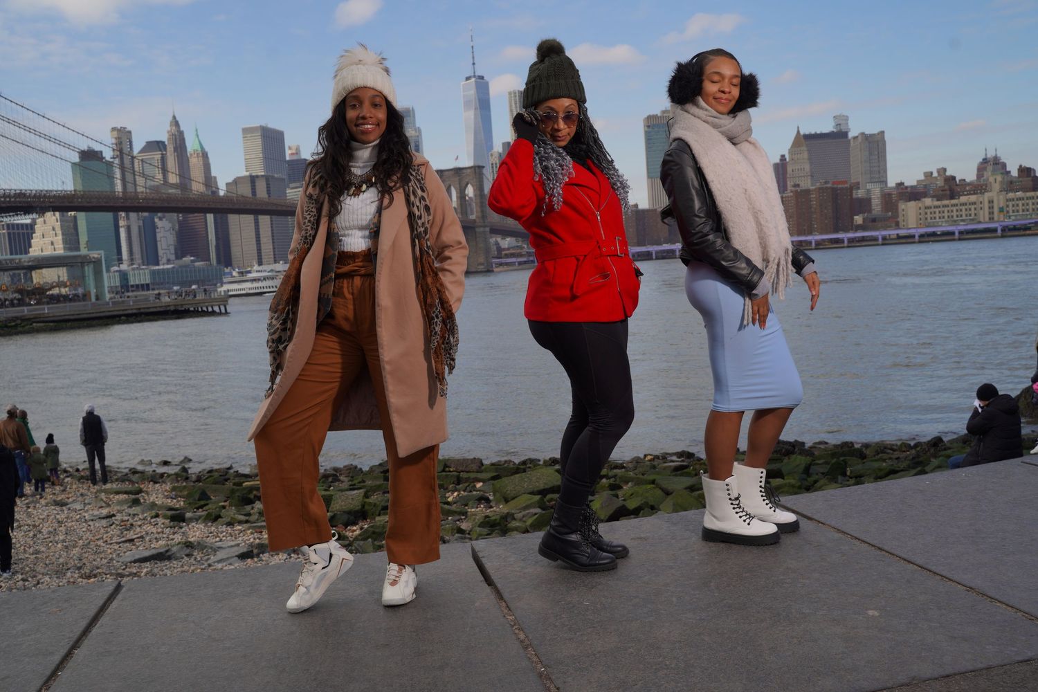 Group posing and taking pictures along East River with Manhattan skyline backdrop.