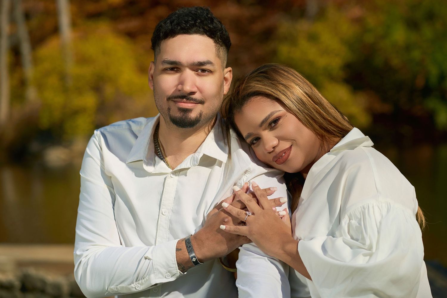 A couple in white outfits share an intimate embrace during their engagement photoshoot.