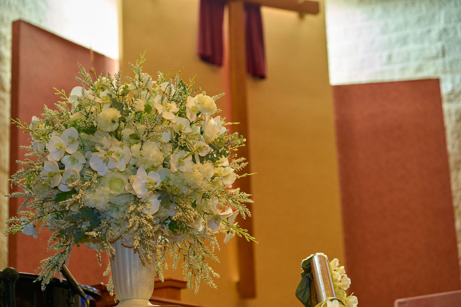 An elegant floral arrangement in a white vase against warm-toned walls.