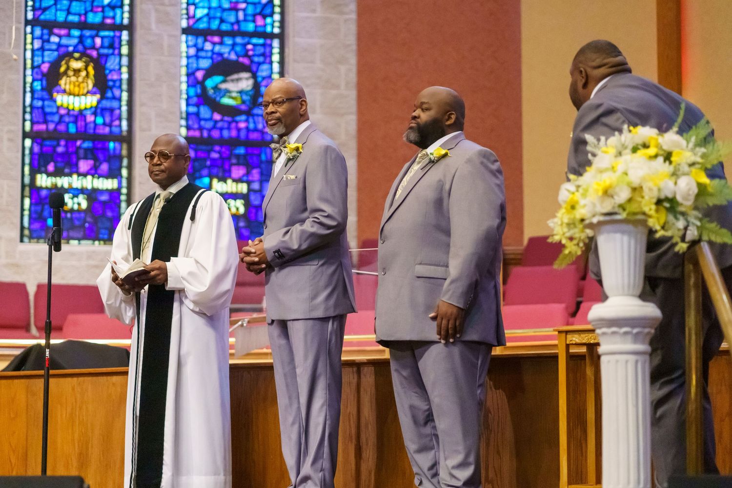 Traditional church wedding ceremony with clergy and wedding party at altar.
