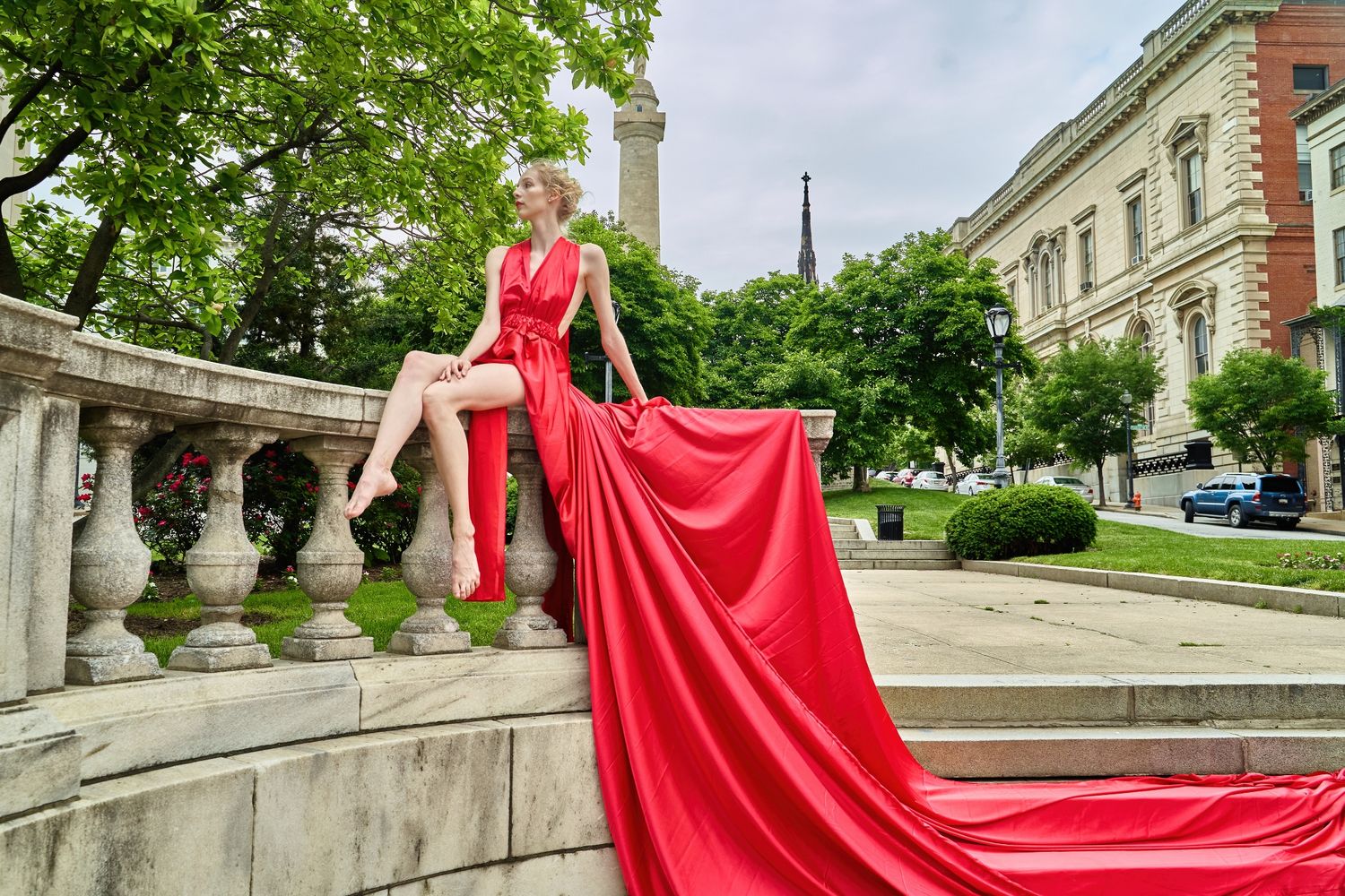 Flowing red dress photographed against classic stone architecture and greenery.