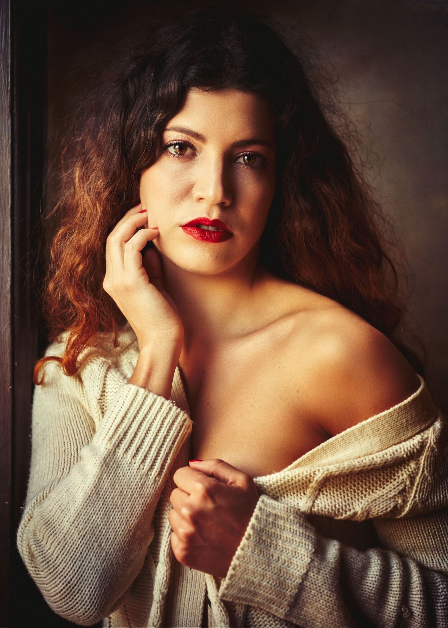 Artistic portrait series in cozy cream sweater against dark background with dramatic lighting.