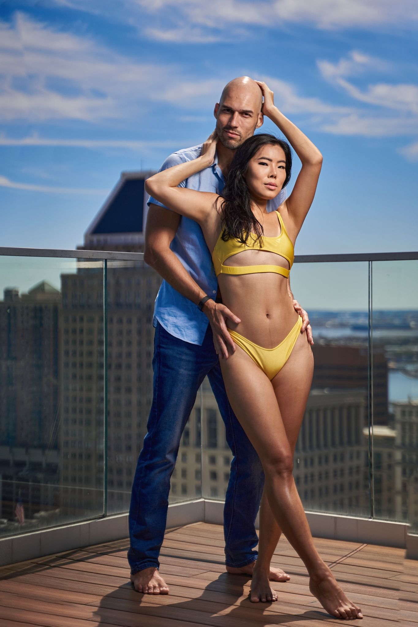 Yellow swimsuit photoshoot on an urban rooftop deck with cityscape views.