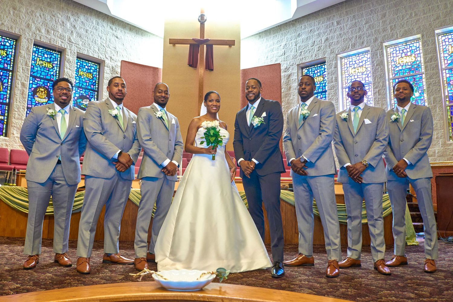 Wedding party members in gray suits and red shoes pose together for formal photos.