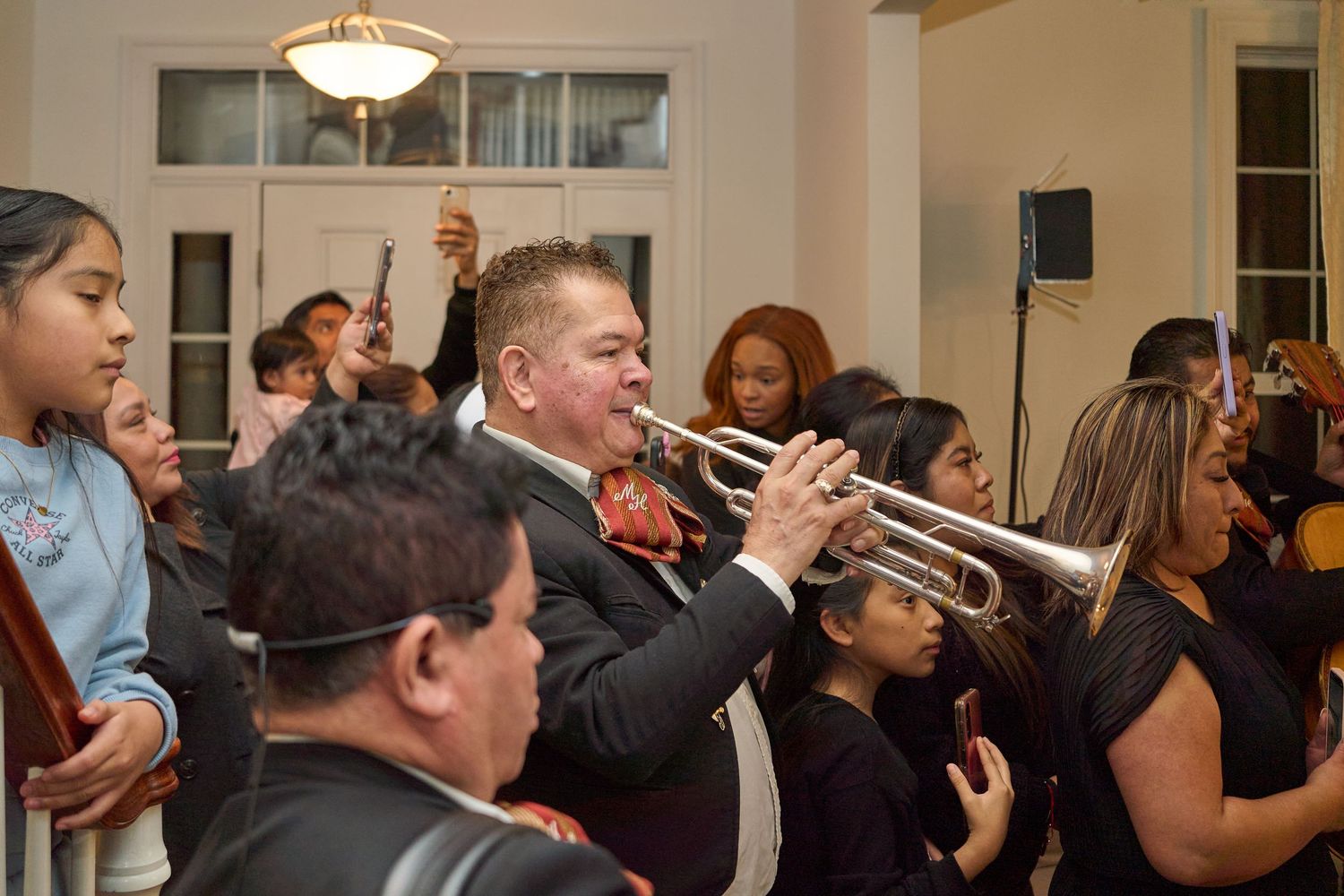 A trumpet player performs at an indoor event while guests watch and listen.