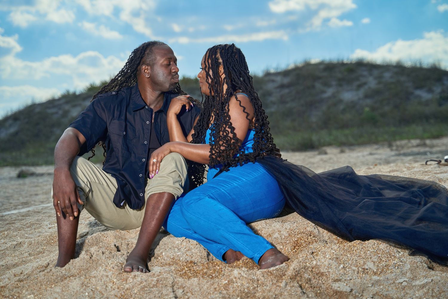 Couple relaxing on a sandy beach during a bright summer day with clear blue skies.