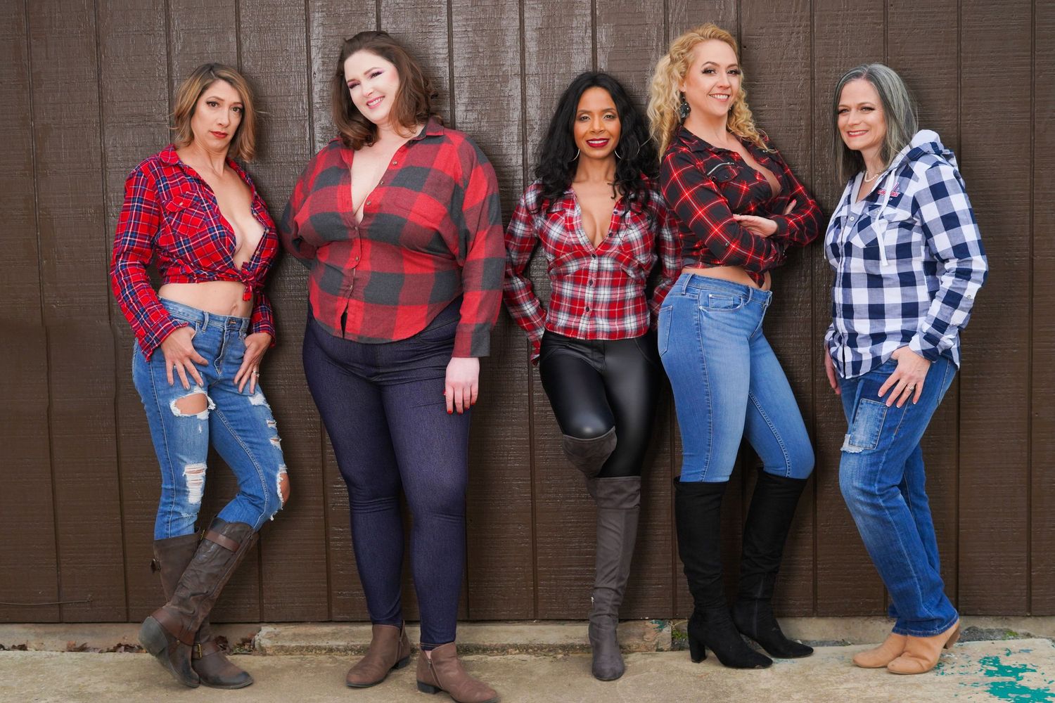 Line of women in plaid shirts and jeans posing against rustic wooden wall.