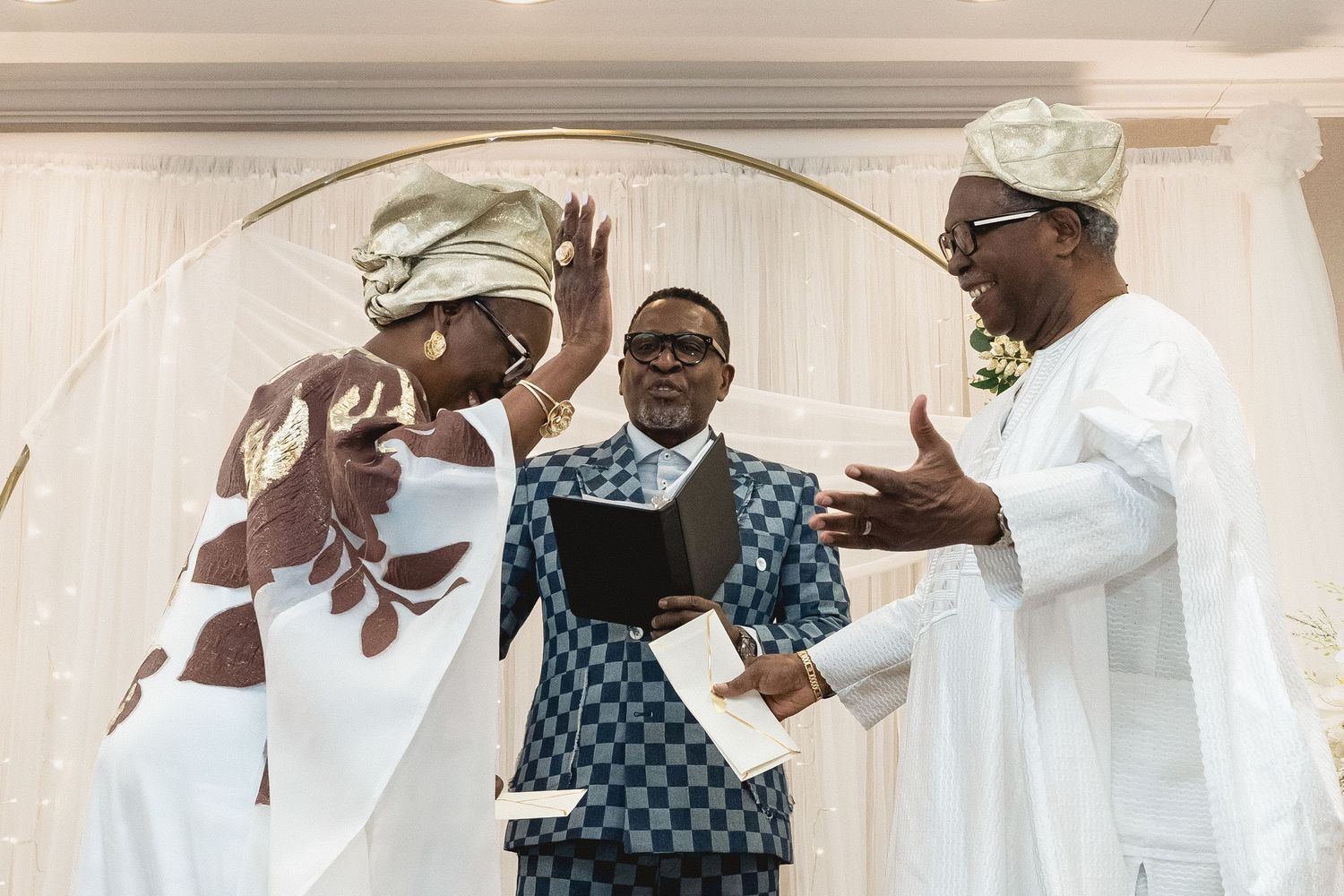 Wedding guests in traditional African clothing interact during reception celebration.