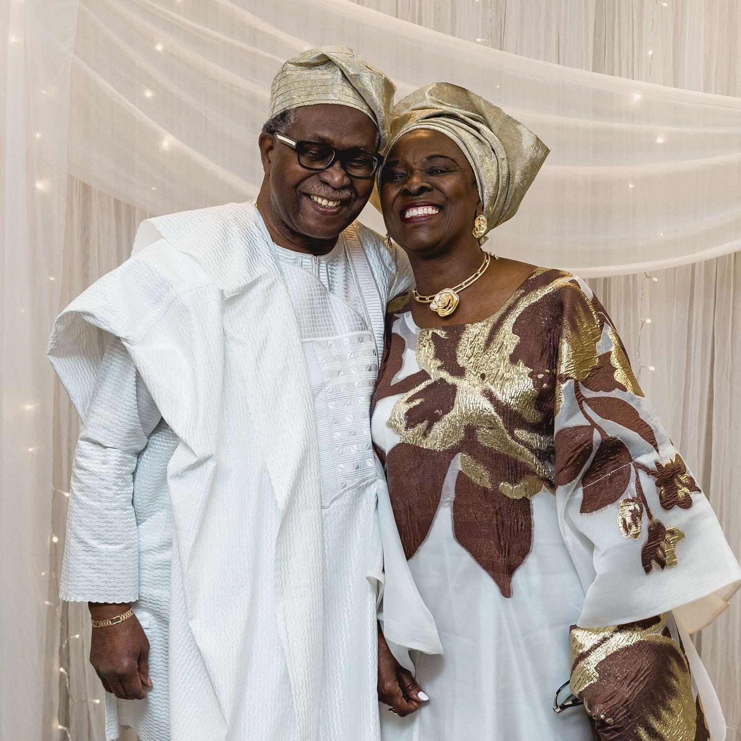 Wedding guests in traditional white and gold attire share joyful moments.