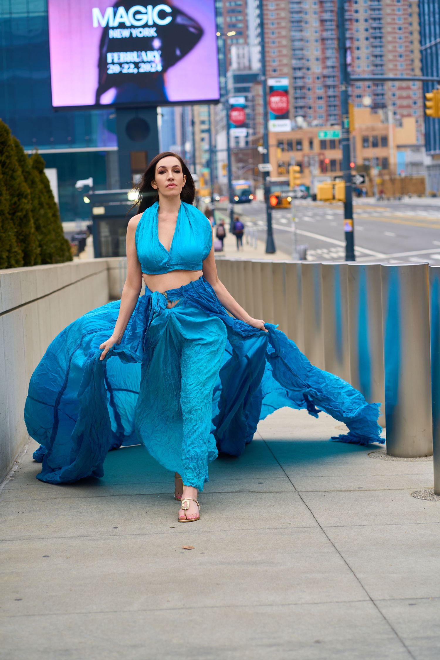 Flowing blue dress movement captured against urban cityscape with neon signs.