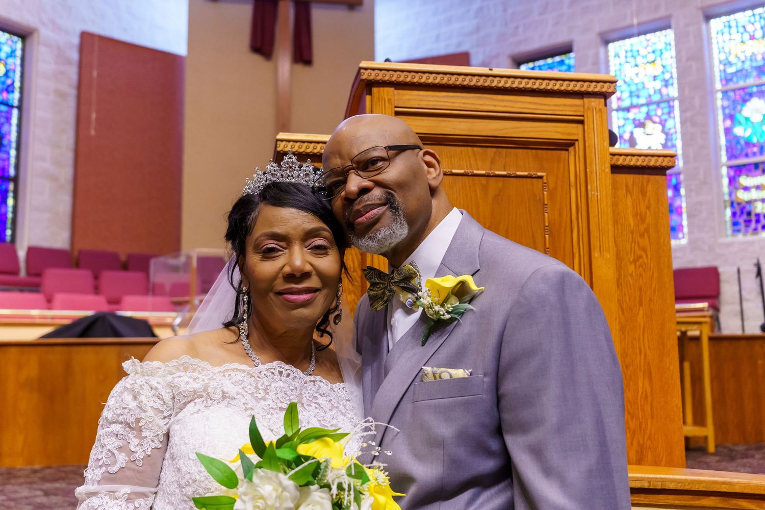Wedding ceremony in church with colorful stained glass windows.