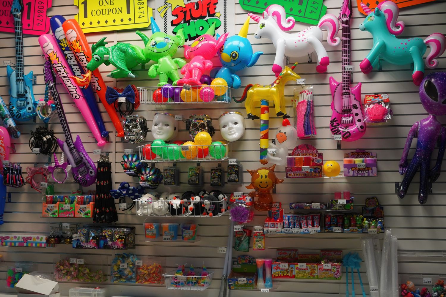 Colorful stuffed animals and toys displayed on retail store wall shelving.