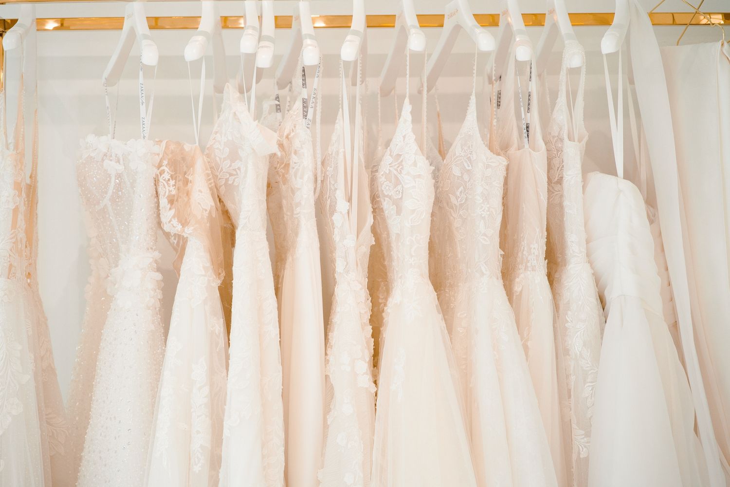 Elegant white wedding dresses hanging in a bridal boutique showroom.