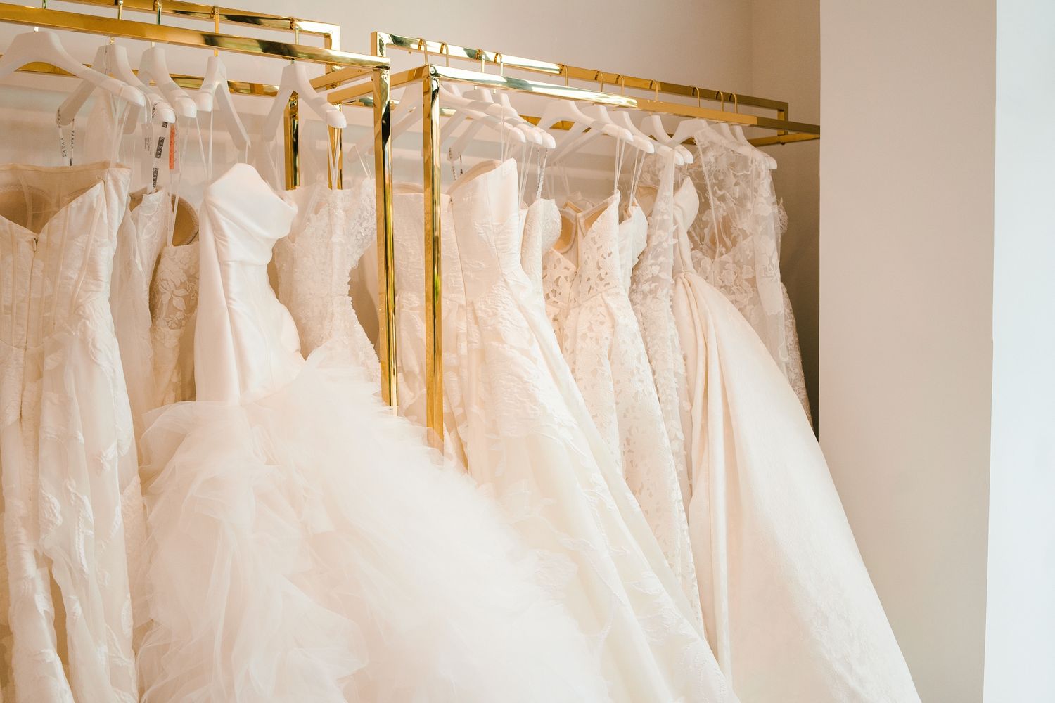 Row of elegant white wedding dresses hanging on display in bridal boutique.