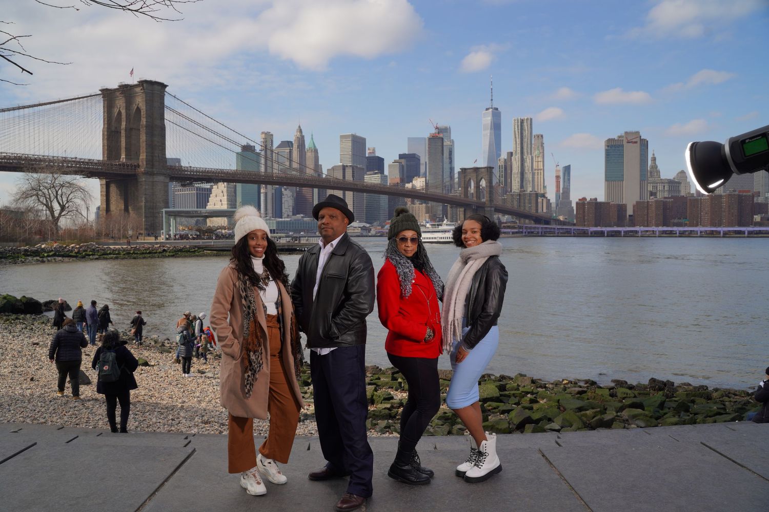 Multiple people taking photos and enjoying views at Brooklyn Bridge Park waterfront.