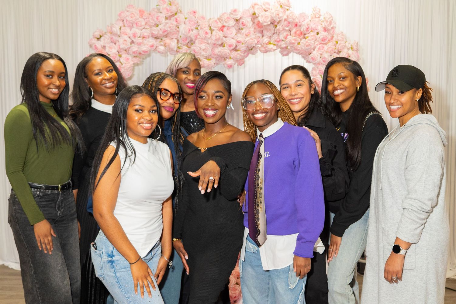 Group photo of friends celebrating special occasion against floral backdrop.