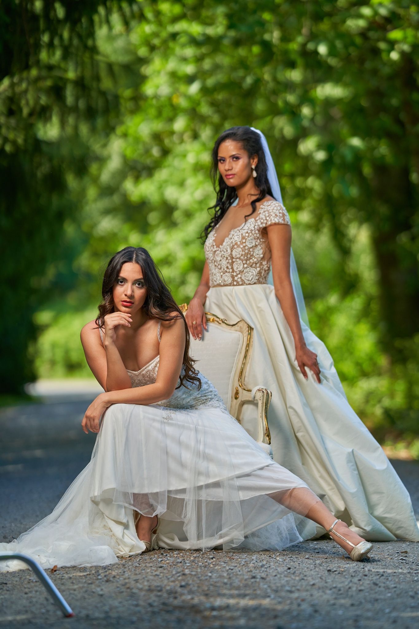 Two elegant wedding dresses showcased in an outdoor photoshoot with a lush green forest backdrop.