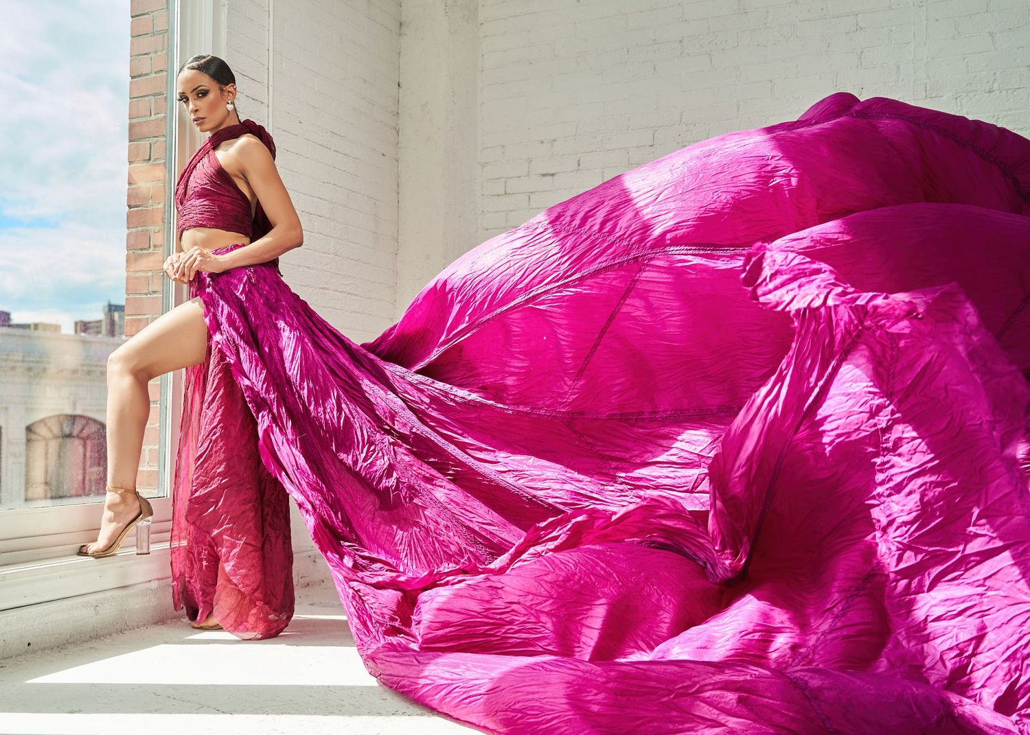 Model in flowing magenta dress creates dramatic movement shots in urban setting.