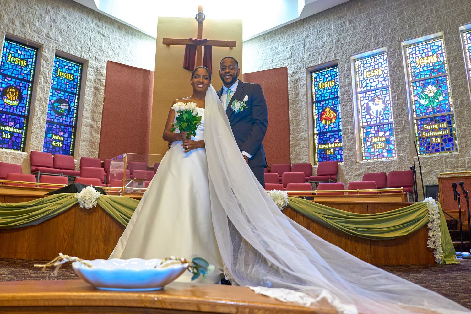 Wedding ceremony venue with stained glass windows and traditional church decorations.