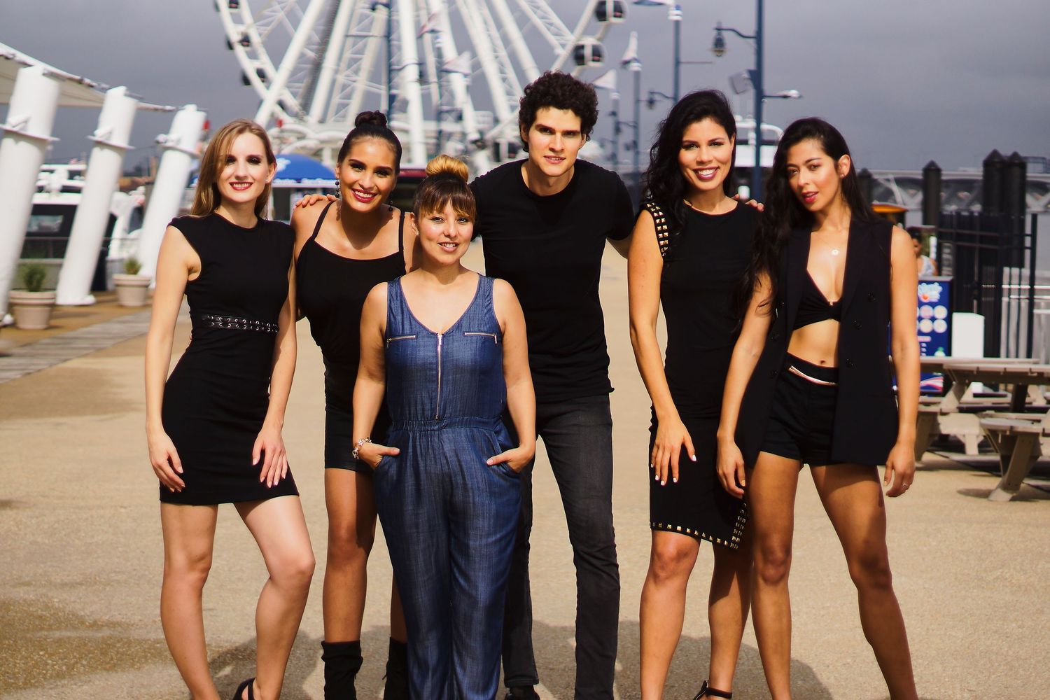 Group photo shoot with models wearing black and navy outfits by a ferris wheel.