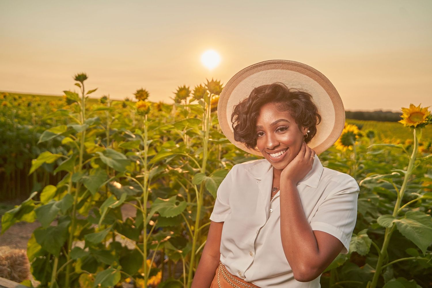 Dreamy portrait in sunflower field during golden hour sunset.