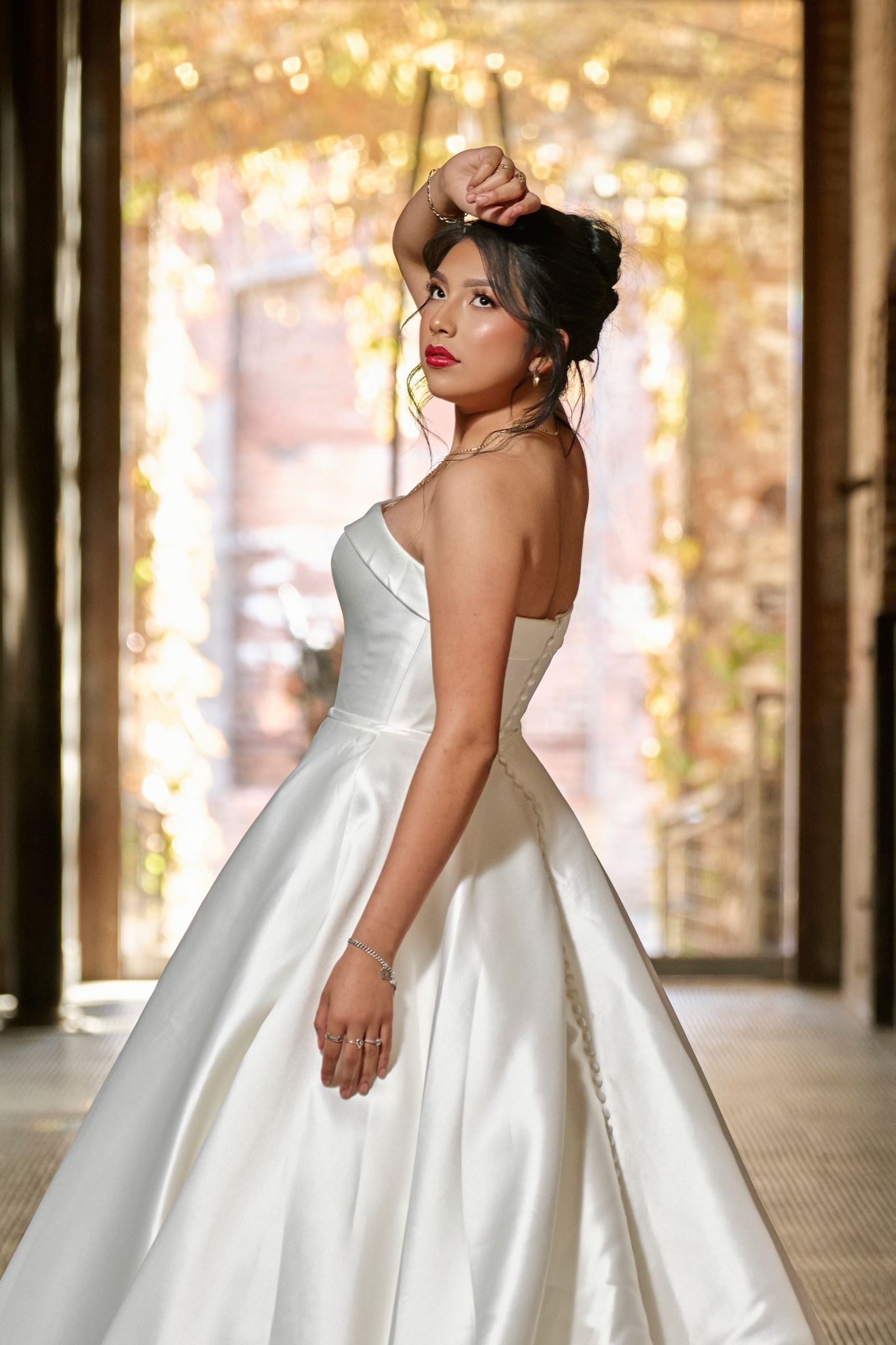 Elegant white wedding gown with full skirt photographed against glowing golden backdrop.