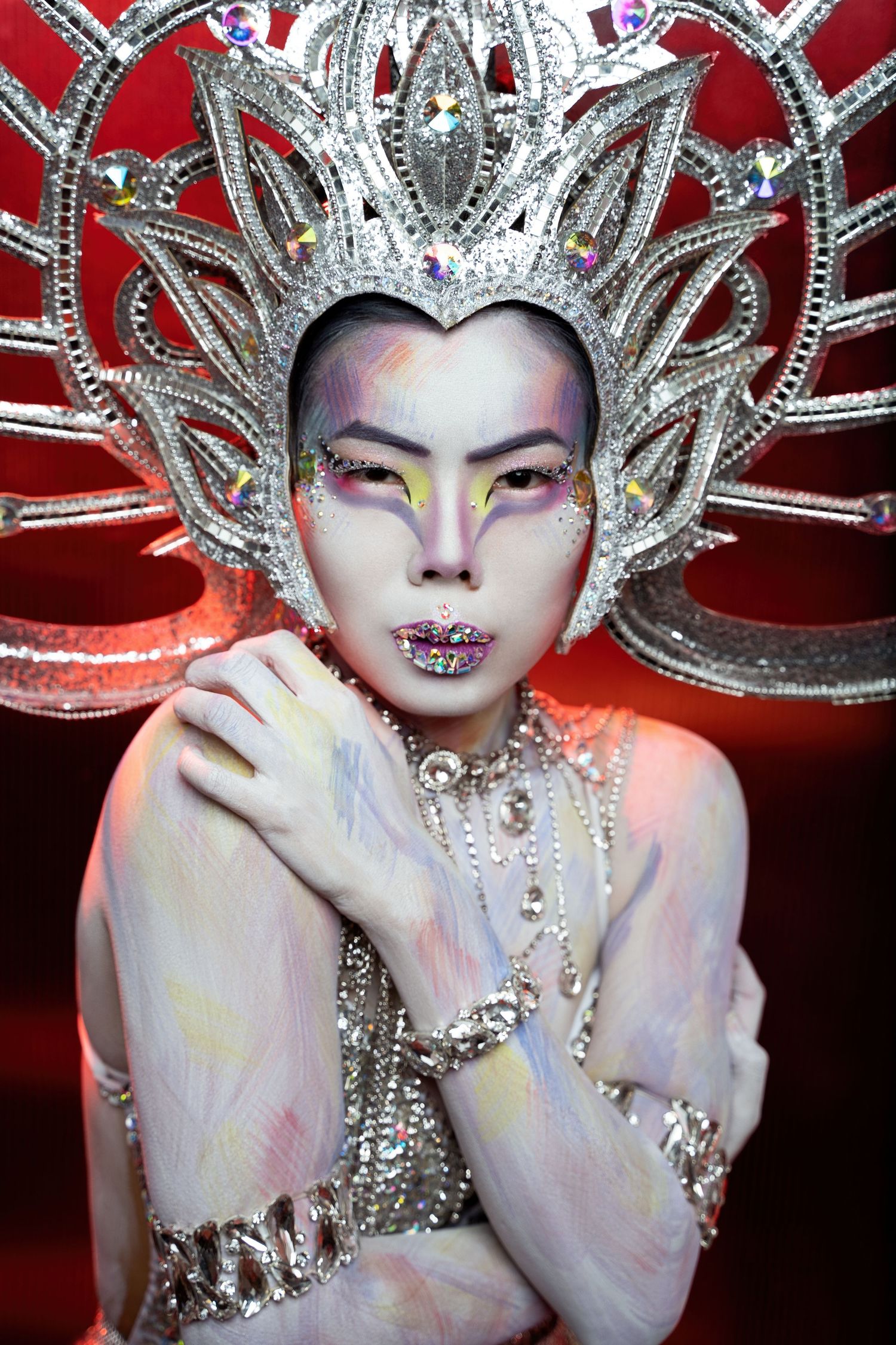 Artistic portrait with elaborate silver crown headpiece and dramatic white makeup.