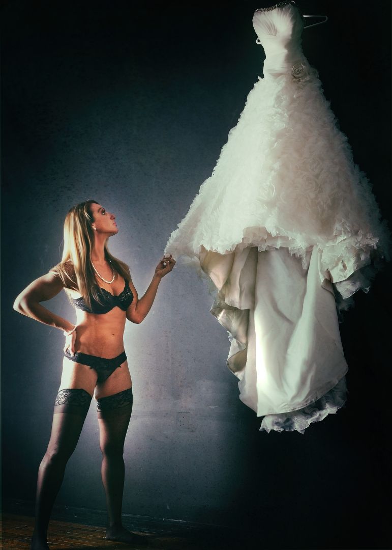 Artistic boudoir photography with flowing white dress and dramatic lighting.
