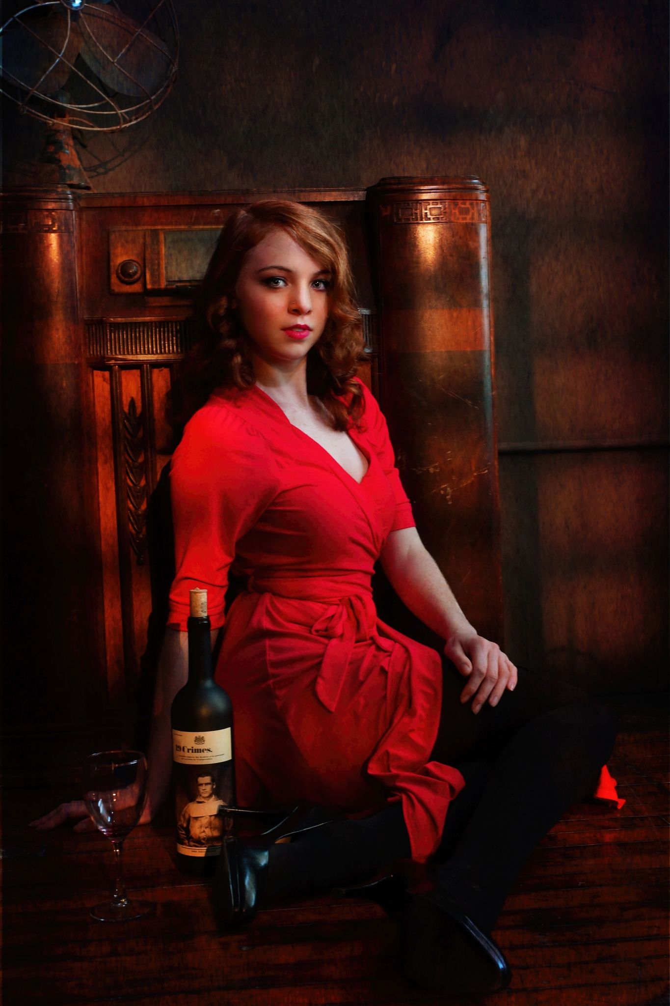 Moody portrait series in red dress with vintage decor and wine bottle props.