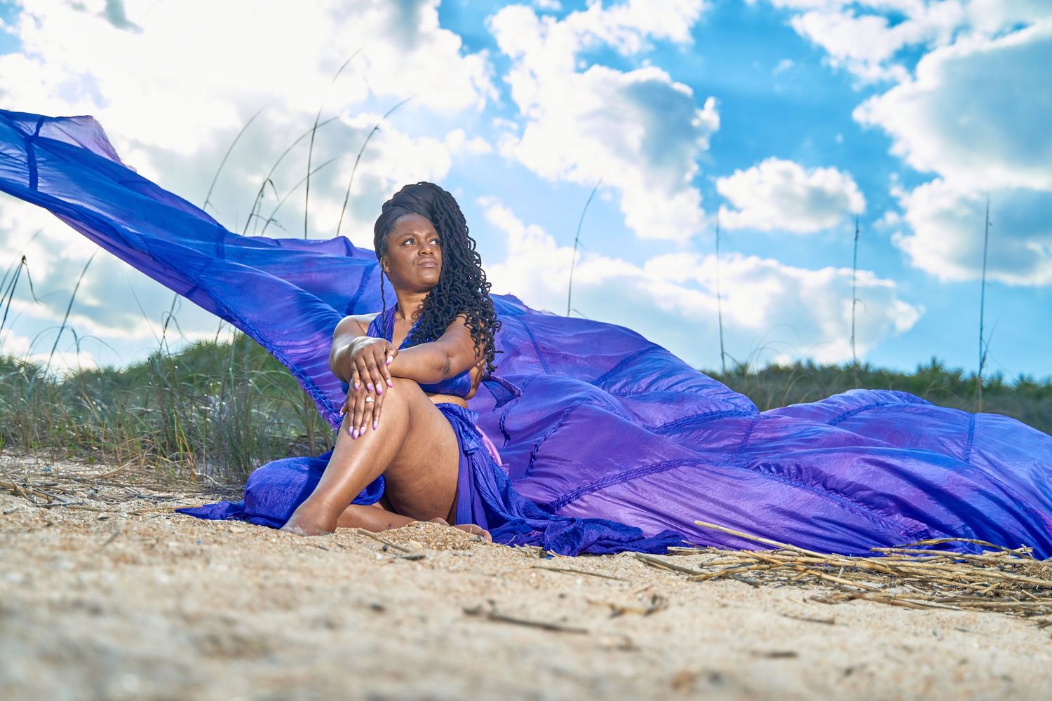Royal blue fabric flowing dramatically across sandy beach landscape.