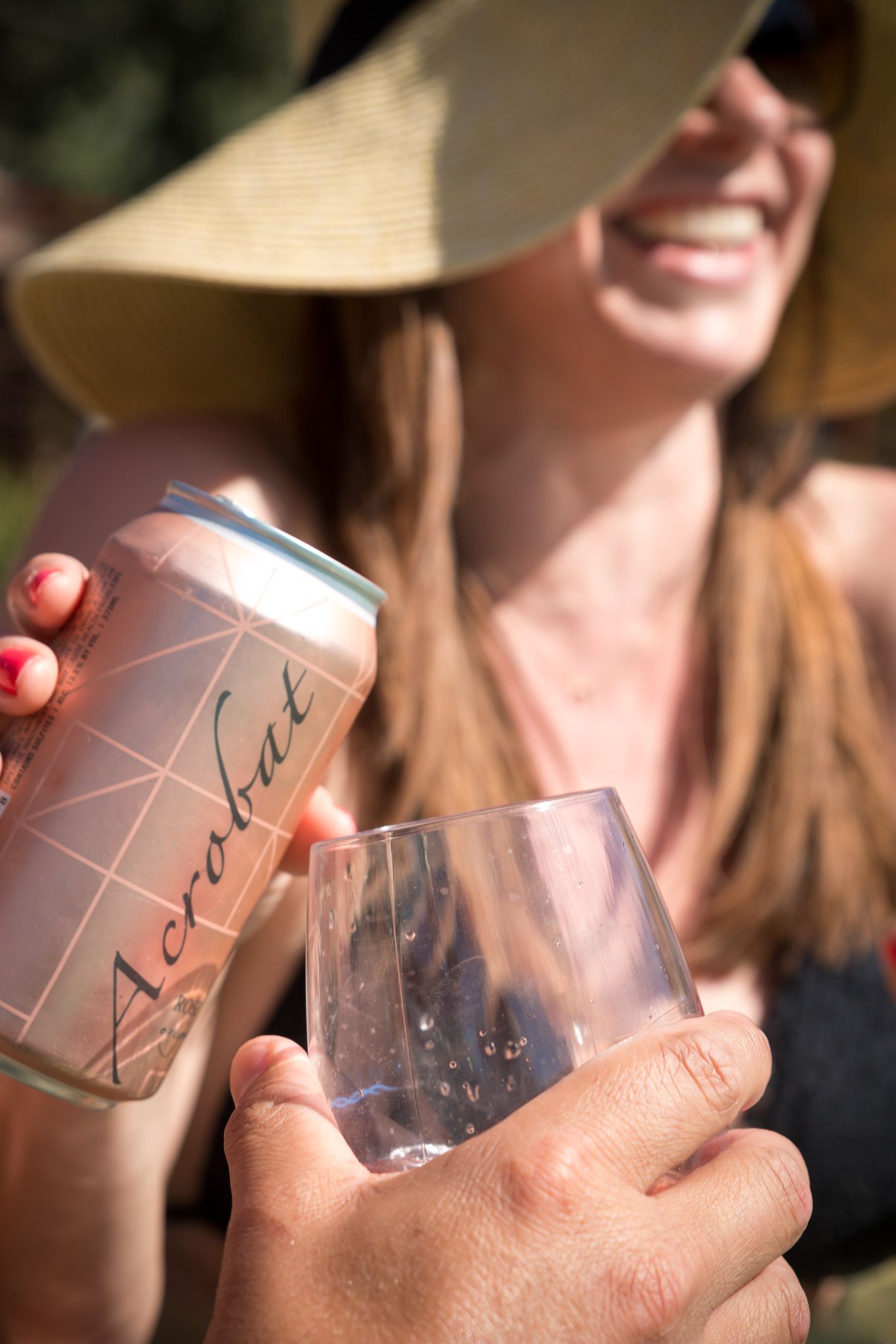 Hands holding canned beverages while socializing outdoors in summer.