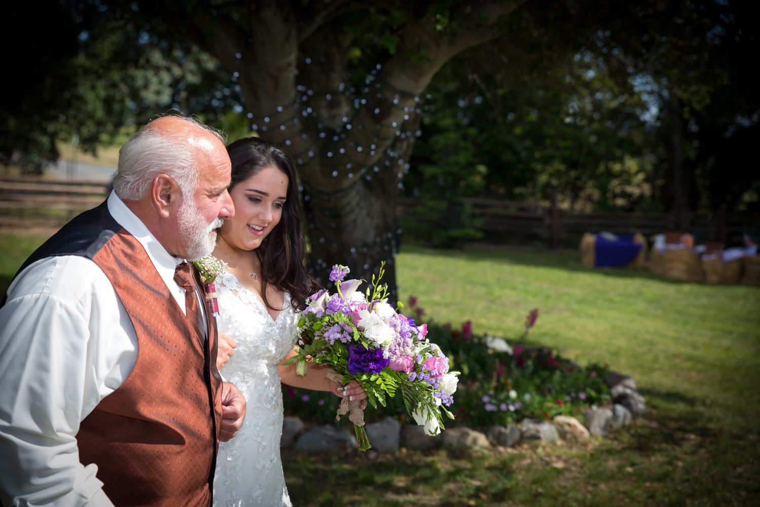 An outdoor wedding moment captured with a shower of bubbles floating through the sunlit garden.