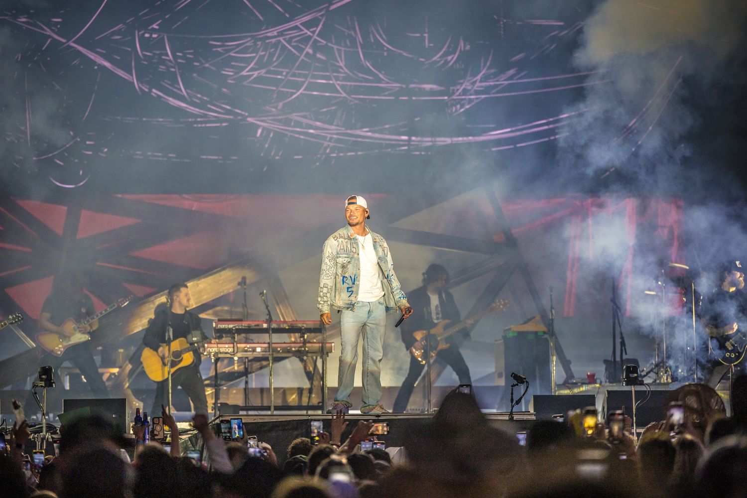 Concert performer on stage surrounded by smoke effects and dramatic lighting during an evening performance.