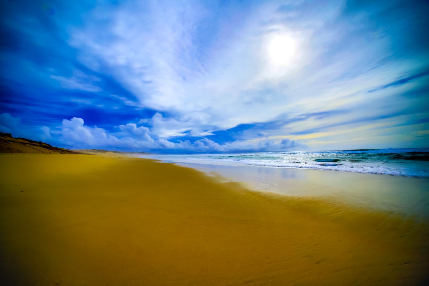 Vibrant beach landscape with golden sand and blue sky reflecting in the ocean waves.