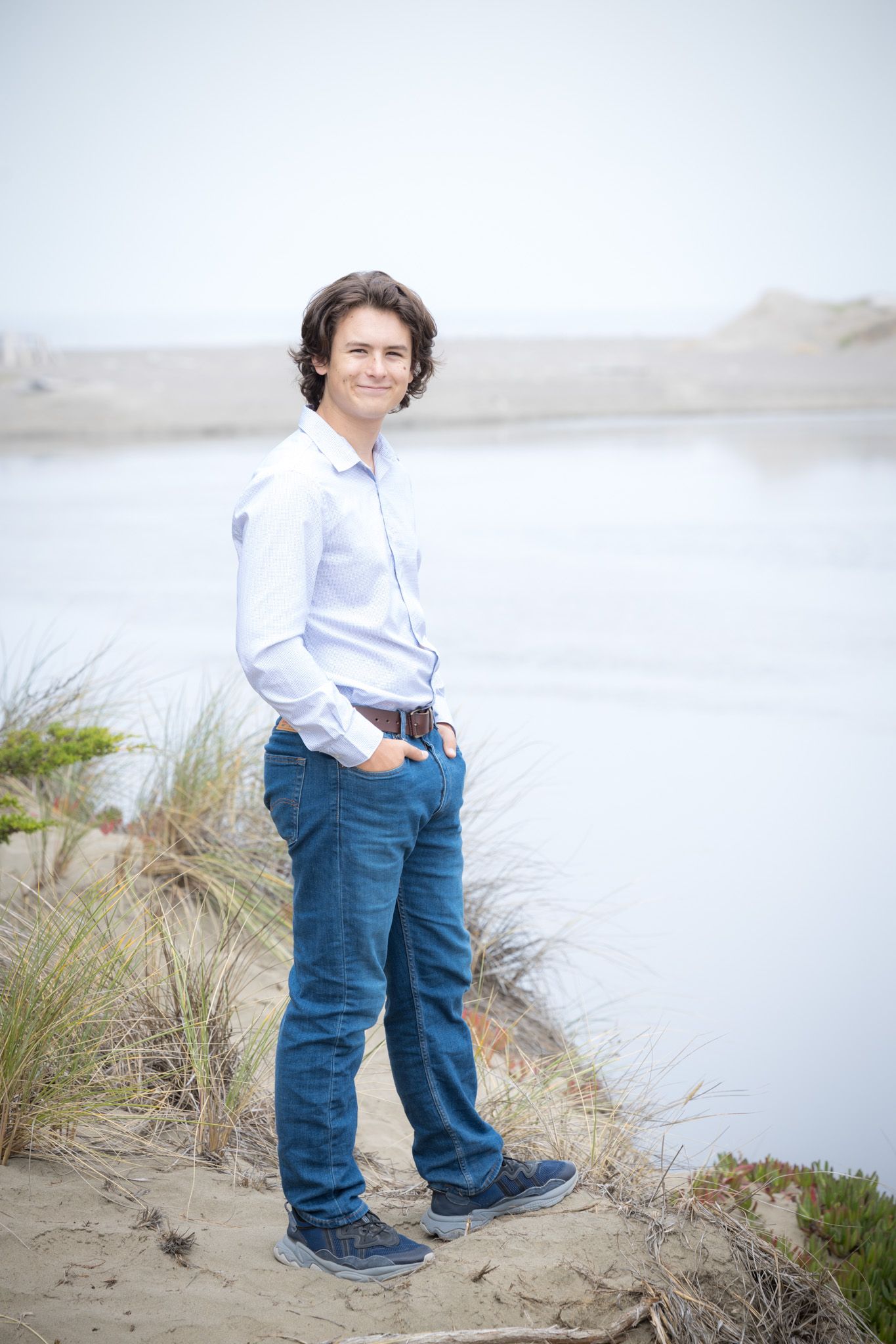 Full length portrait of person in blue shirt and jeans on coastal path.