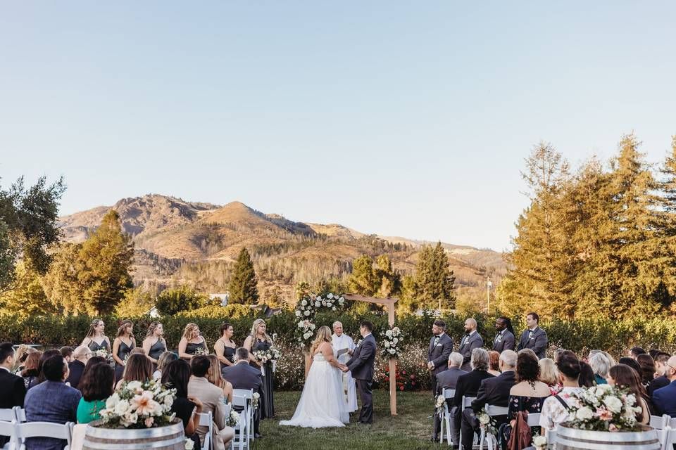 Panoramic view of an outdoor wedding ceremony in a scenic mountain setting during golden hour.