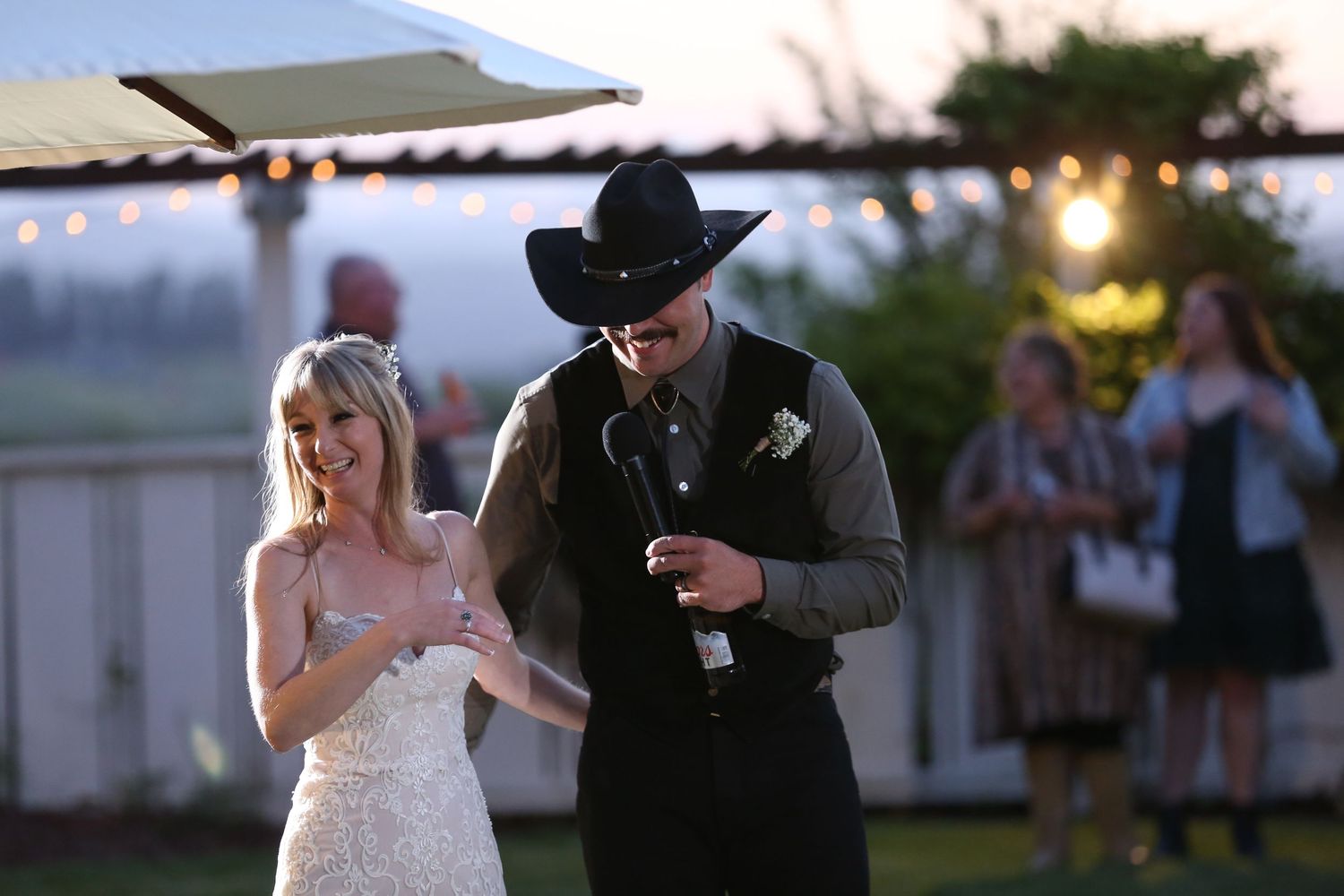 A couple performs their first dance outdoors at their rustic country-themed wedding reception at sunset.