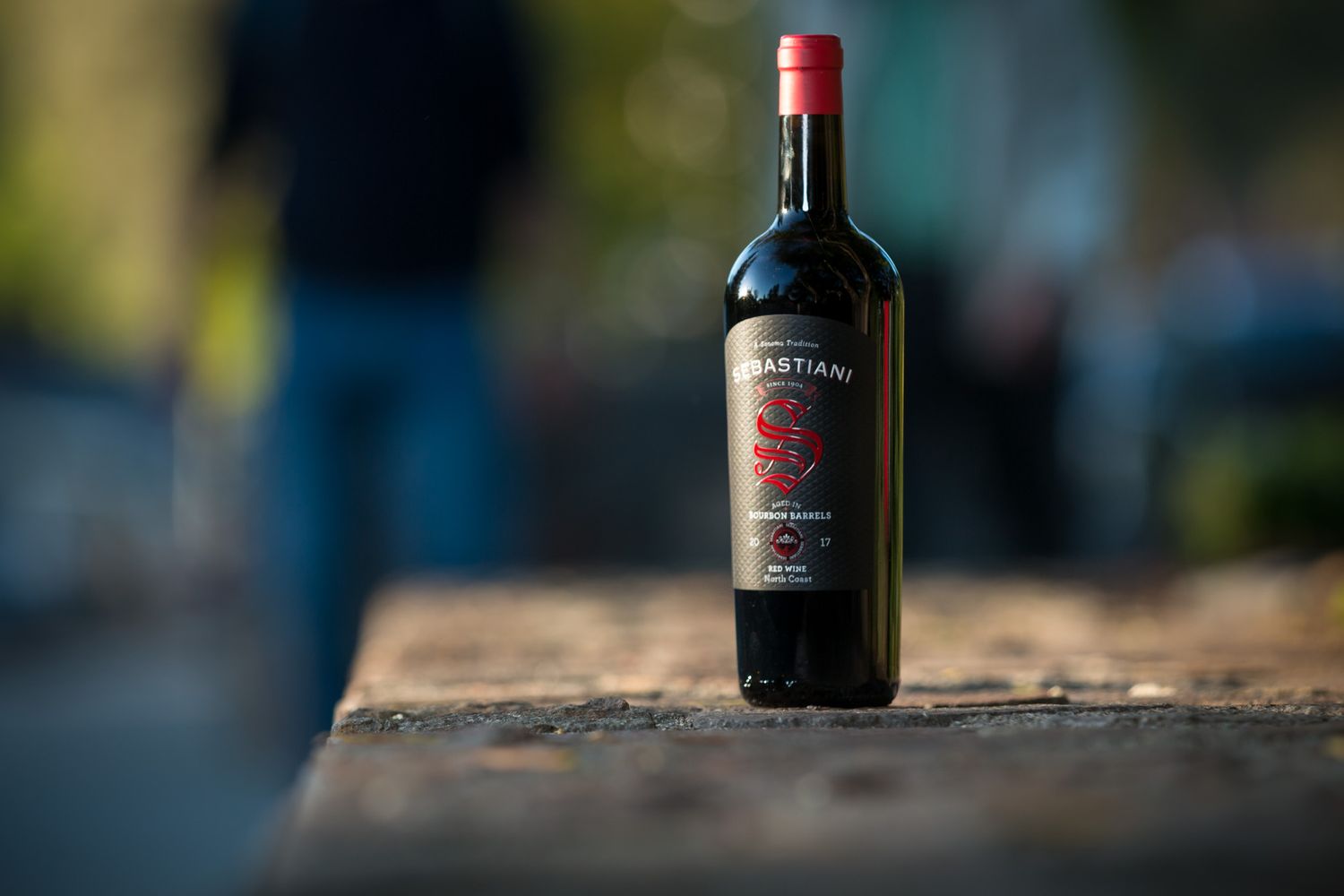 Red wine bottle with vintage label photographed at sunset with bokeh background.