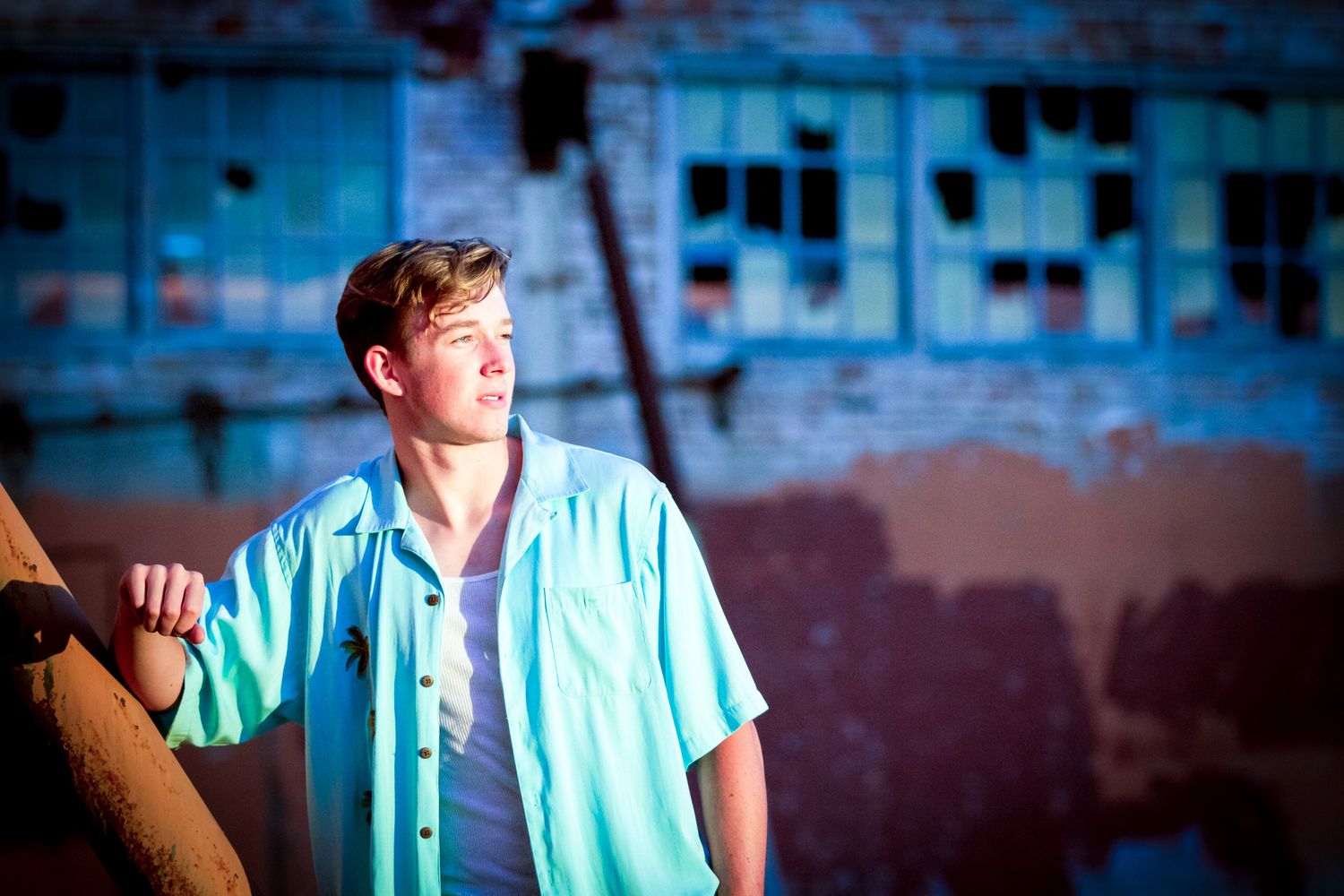 Portrait of person in casual attire against blue urban background at golden hour.