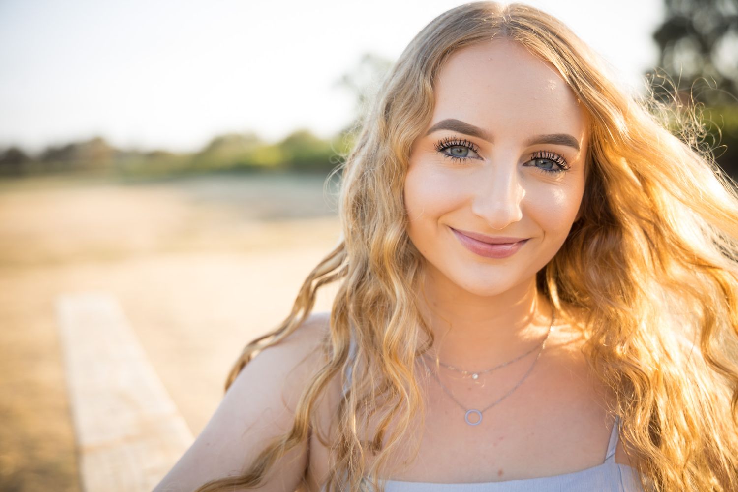 Outdoor portrait of a person with flowing blonde hair in natural sunlight at golden hour.