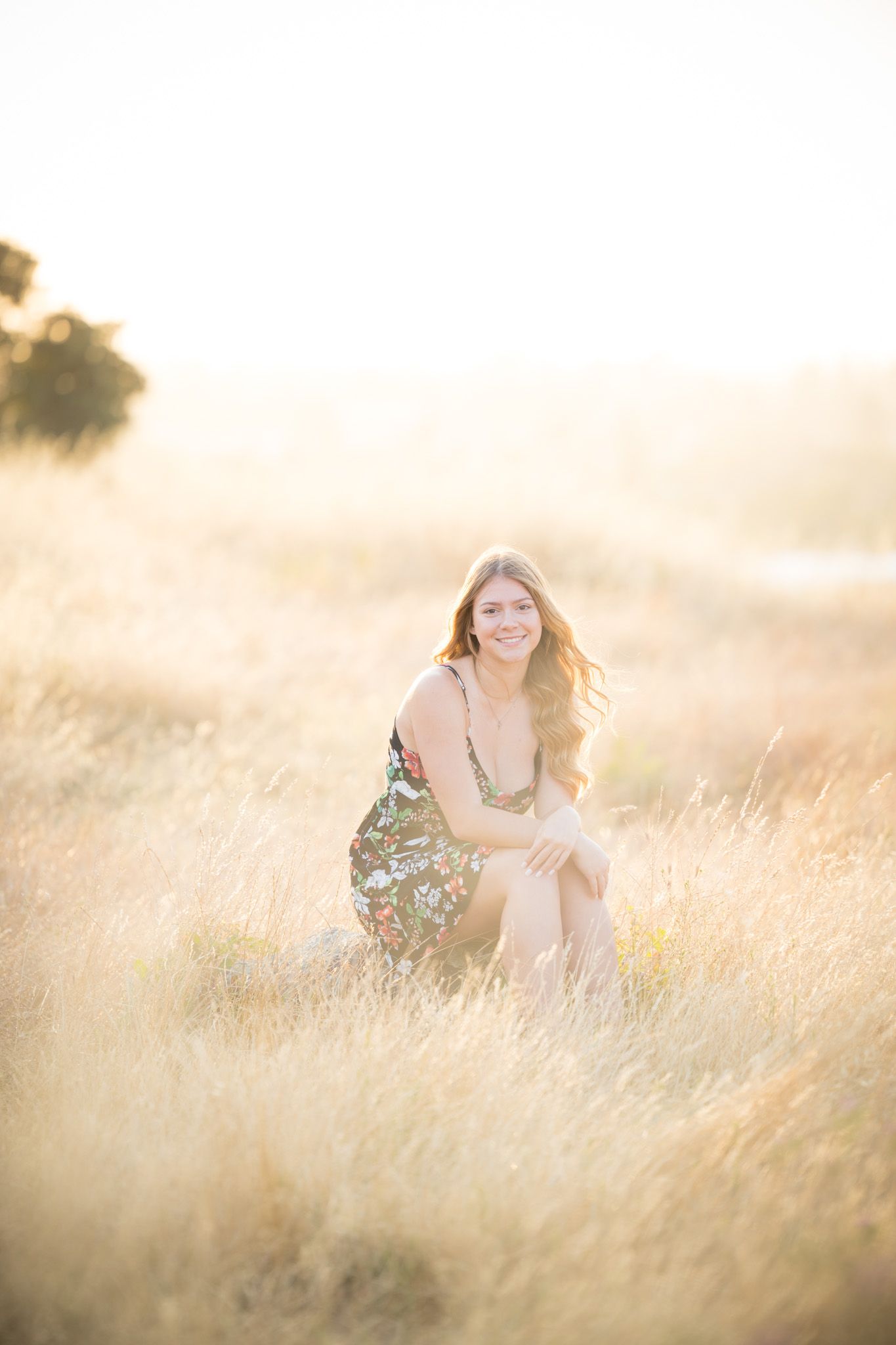 Dreamy outdoor portrait in dry grass field during sunset with soft glowing light.