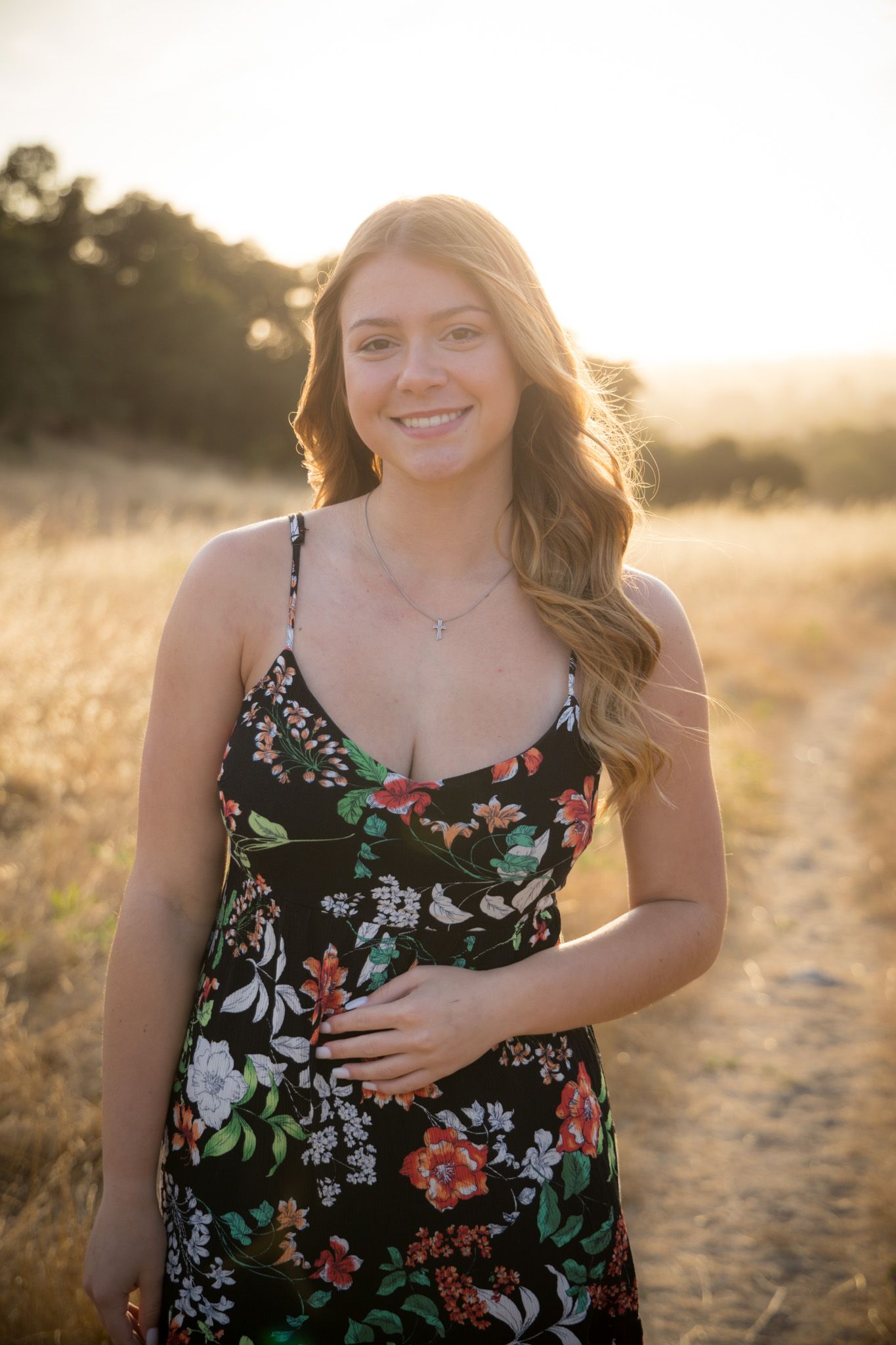 Candid portraits in a floral dress against a warm sunset backdrop.