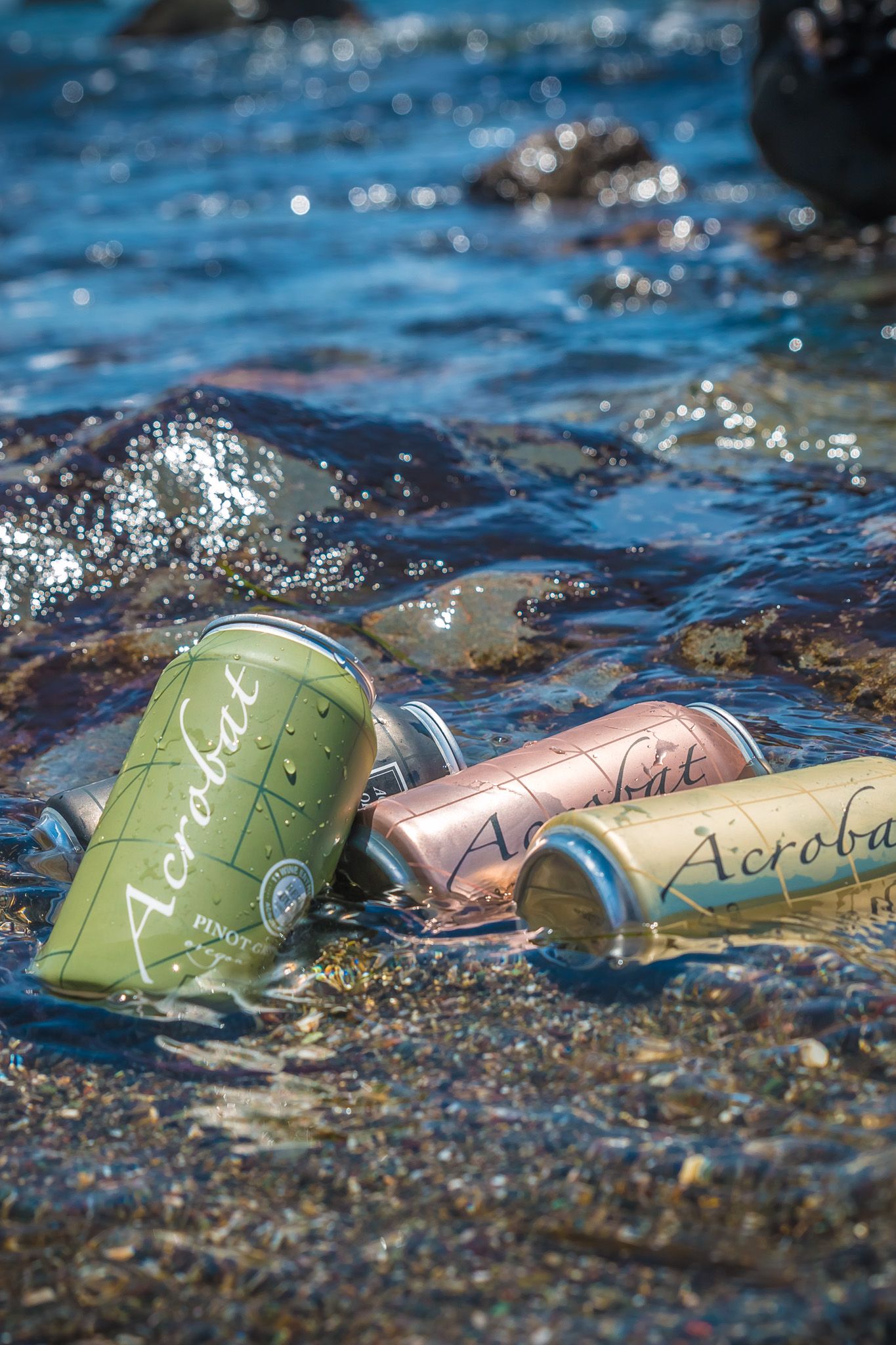 Canned wines floating in sparkling blue water with sunlight reflections.